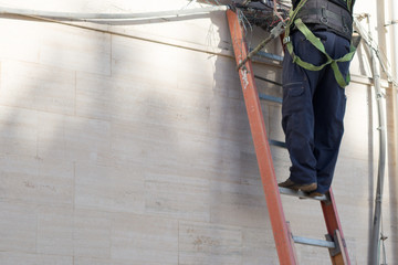 Horizontal View of a Tecnician Working on a Ladder With Safety Tolls. Empty Space for Words