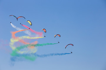 Powered parachutes Air show - multicolored Paratroopers in the sky with trail of italian flag...