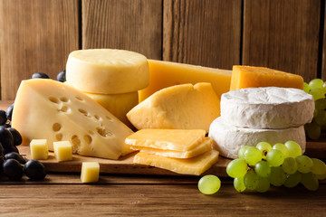 Various types of cheese on dark rustic wooden background.