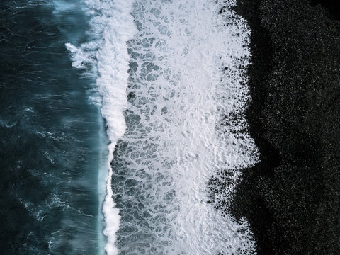 Aerial view of waves on black sand beach