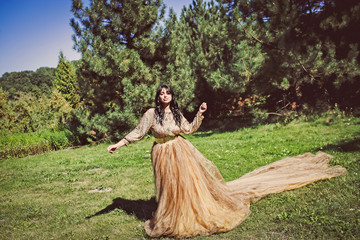 Красивая девушка брюнетка в элегантном платье в парке