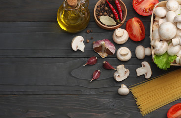 Fototapeta na wymiar Italian food background, with tomatoes, parsley, spaghetti, mushrooms, oil, lemon, peppercorns on dark wooden table. Top view