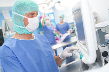 doctor or surgeon examinig screen of sophisticated medical equipment