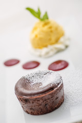 delicious chocolate hot cake with fruit sauce and vanilla ice cream on white plate, chocolate fondant