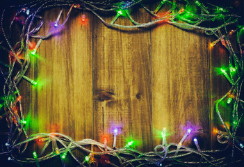 Colorful christmas lights decorate around square wooden frame with center copy space for texts and other holiday design on wood background