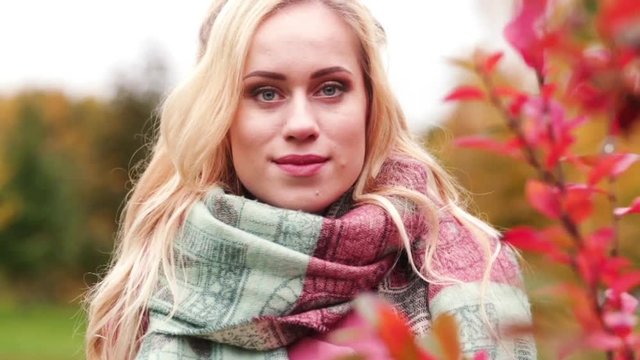 beautiful blonde girl in warm scarf on red leaves background