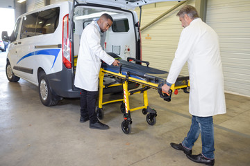 Paramedics loading stretcher into ambulance