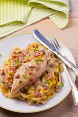 Chicken breast and egg noodles with bacon and mushrooms in creamy sauce. vertical