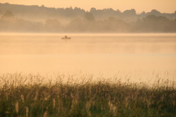 Naklejka premium A magnificent dawn on the river, a fisherman in a boat