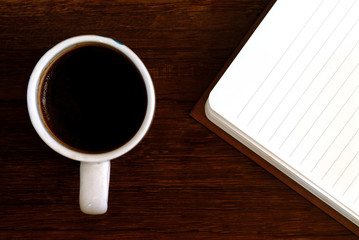 coffee cup with notebook on wooden table