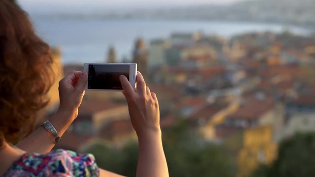 Woman is taking pictures of the city from a viewpoint. 4K, UHD
