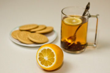 Transparent cup of tea with lemon on white background.