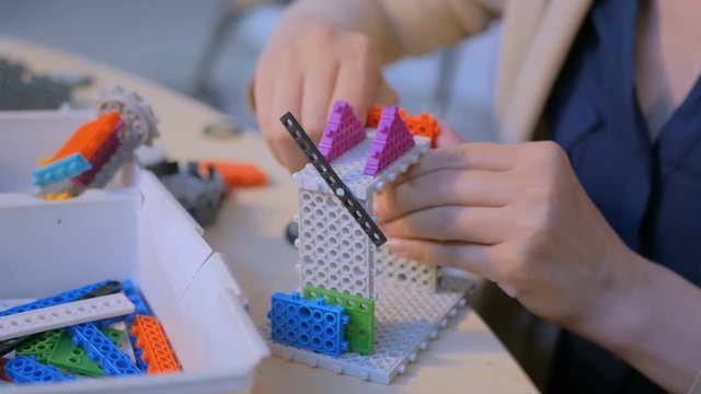 Close up shot of woman hands playing with colorful plastic blocks constructor