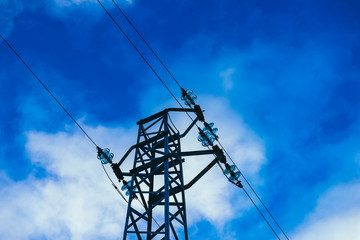 Photo depicting one high-voltage powerful electricity tower with wires on cloudy blue bright sky.
