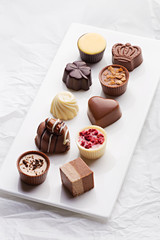 Chocolate pralines assortment on a white background. Selection of finest white, milk and dark chocolate.