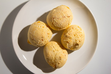 Pao de Queijo is a cheese bread ball from Brazil. Also known as Chipa, Pandebono and Pan de Yuca. Snacks over white plate, minimalism.
