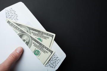 Dollar bribe in an envelope on a black background, empty space for text.