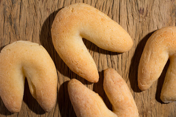 Cheese bread known as Chipa in Brazil, shaped like a horseshoe. Group of snacks on rustic wood, flat lay design.