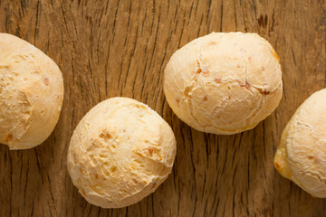 Pao de Queijo is a cheese bread ball from Brazil. Also known as Chipa, Pandebono and Pan de Yuca. Group of snacks on rustic wood, flat lay design.