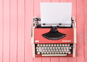 A typewriter on a pink table (top view)