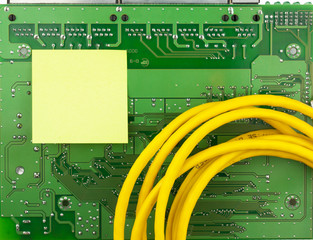 Closeup PCB green board, sticker and yellow patch cord. Place for your text on the sticker