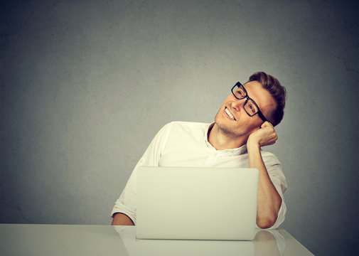 Content man with laptop looking away dreamily