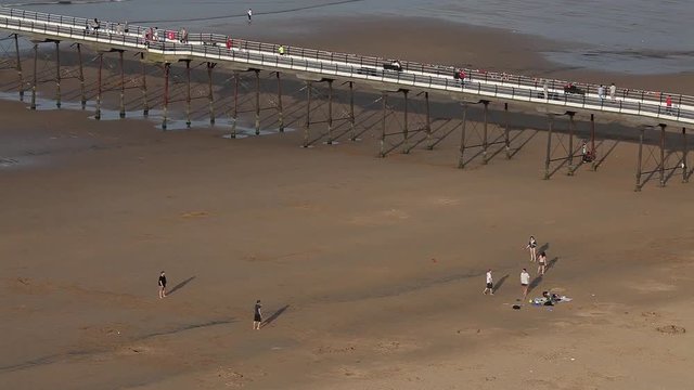 People Walking On Pier & Playing On Beach; Saltburn-By-The-Sea; Saltburn-By-The-Sea, North Yorkshire, England