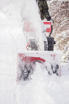 hard working man clearing snow with a snowblower machine plough tool after extreme heavy snow fall storm 