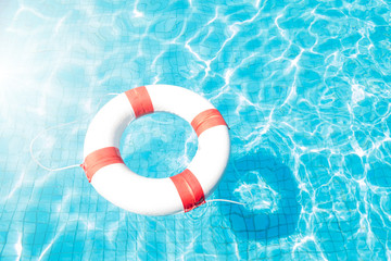 Lifebuoy floating on blue swimming pool.