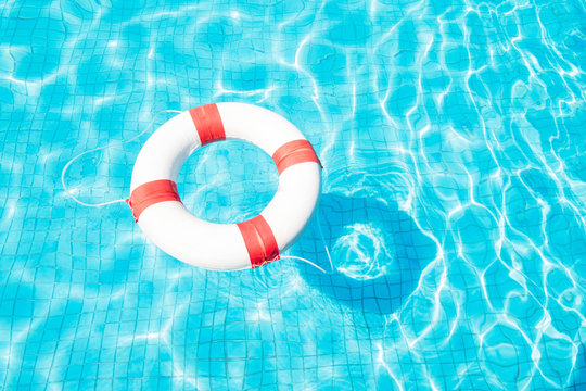 Lifebuoy floating on blue swimming pool.