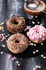 assorted donuts with chocolate frosted, pink glazed and sprinkles donuts.