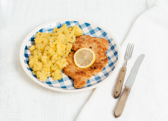 Traditional German or Austrian Wiener Schnitzel or Schnitzel Wiener Art, breaded and pan-fried butterfly cutlet of pork, veal of chicken meat served with slice of lemon and homemade potato salad