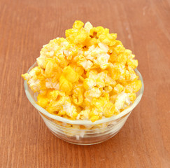 Bowl of fresh popped popcorn isolated on wooden board