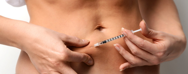 Woman make medical diabetes insulin injection shot into abdomen with single use syringe