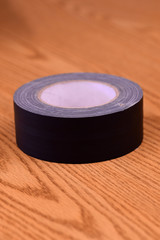 Roll of Black Gaffer's Tape on a Brown Table