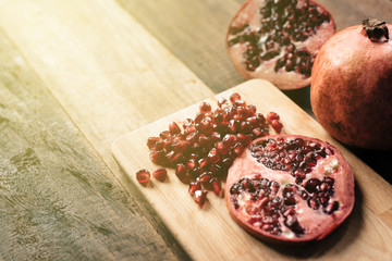 peeled pomegranate fruit nad pomegranate seeds on wooden board and table