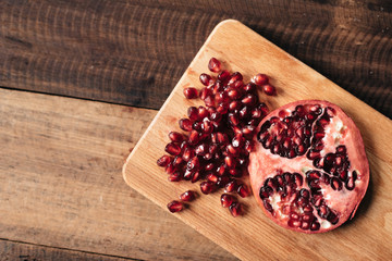 peeled pomegranate fruit nad pomegranate seeds on wooden board and table