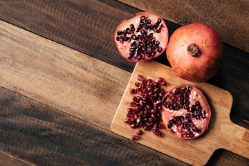 peeled pomegranate fruit nad pomegranate seeds on wooden board and table