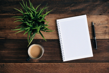 coffee, glasses pen, green plant and empty notebook on wooden table. flat lay top view