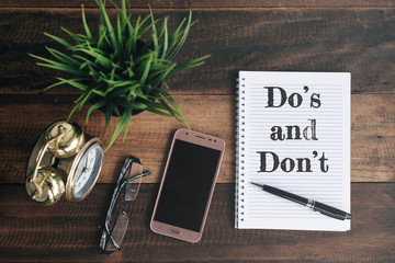 phone, glasses, clock, green plant and notebook with Do's and don't word. lifestyle concept