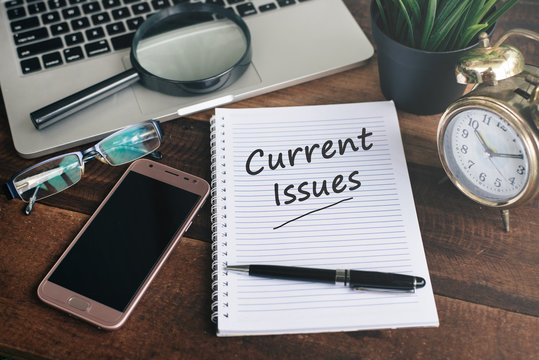 notebook, laptop, smartphone, clock and pen with CURRENT ISSUES word on a wooden background. current issues concept