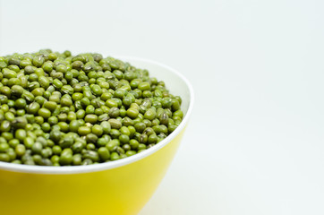 Mung beans in yellow bowl isolated on white background. also known as moong bean, green gram, green bean. its in legume family species