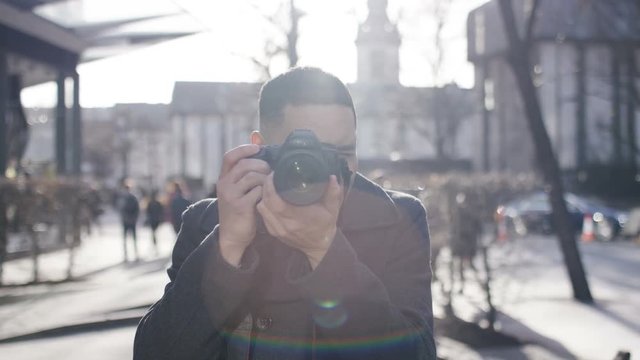 Mixed race man with digital camera takes a photo fo the viewer