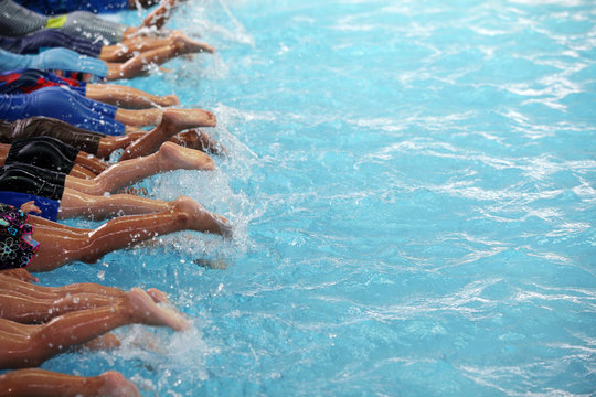 leg shot of children learning to swim in swimming pool