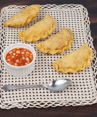 Colombian empanada with spicy sauce on wooden background