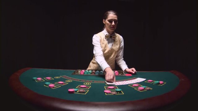 Casino professional dealer shuffles the poker cards and performing trick with cards. Black background. Slow motion