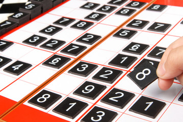 A hand holding a tiles  on a sudoku grid