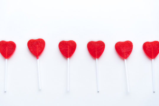 Red Valentine heart lollipops in a row across white background