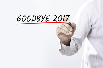 Businessman hand writing goodbye 2017 with red marker on transparent wipe board, business concept