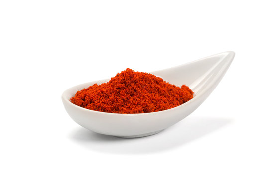 Bowl of ground red pepper spice in bowl isolated on white
